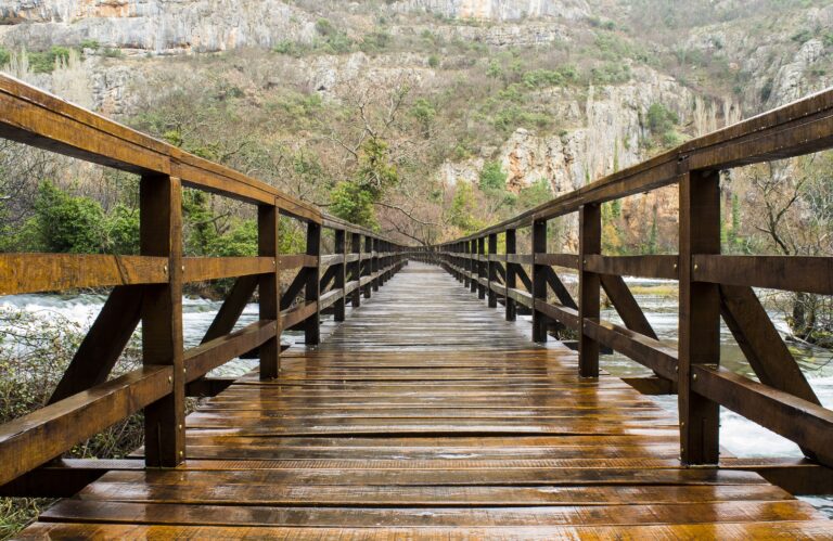 A wooden bridge surrounded by rocks covered in greenery in Krka National Park in Croatia